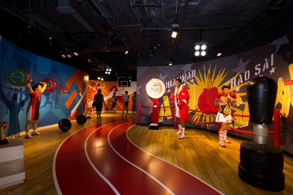 박물관에 있는 권투 선수 두 명의 왁스 피규어에는 권투 장비가 전시되어 있습니다. 한 피규어는 빨간색 가운을 입고, 다른 피규어는 권투 반바지와 장갑을 착용합니다.