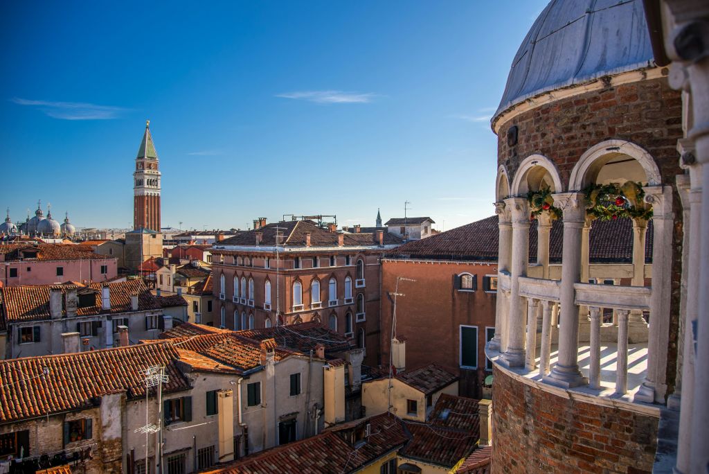 붉은 타일, 산 마르코 대성당의 종탑, 맑고 푸른 하늘이 있는 베네치아 건물의 옥상 전망.