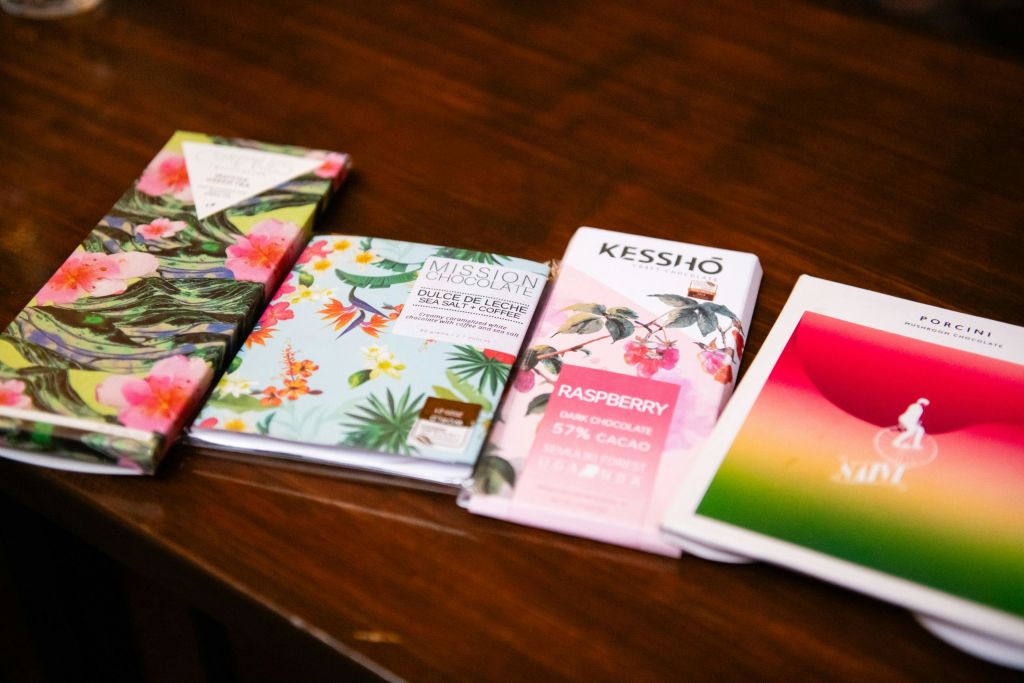 다채롭고 예술적인 포장을 한 5개의 초콜릿 바가 나무 테이블에 전시되어 있습니다.