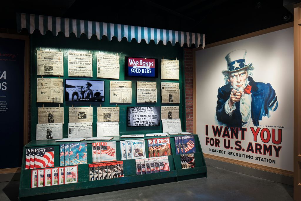 "War Bonds Sold Here" 표지판, 다양한 역사 문서, 잡지, 대형 "I Want You for U.S. Army" Uncle Sam 포스터가 있는 전광판.