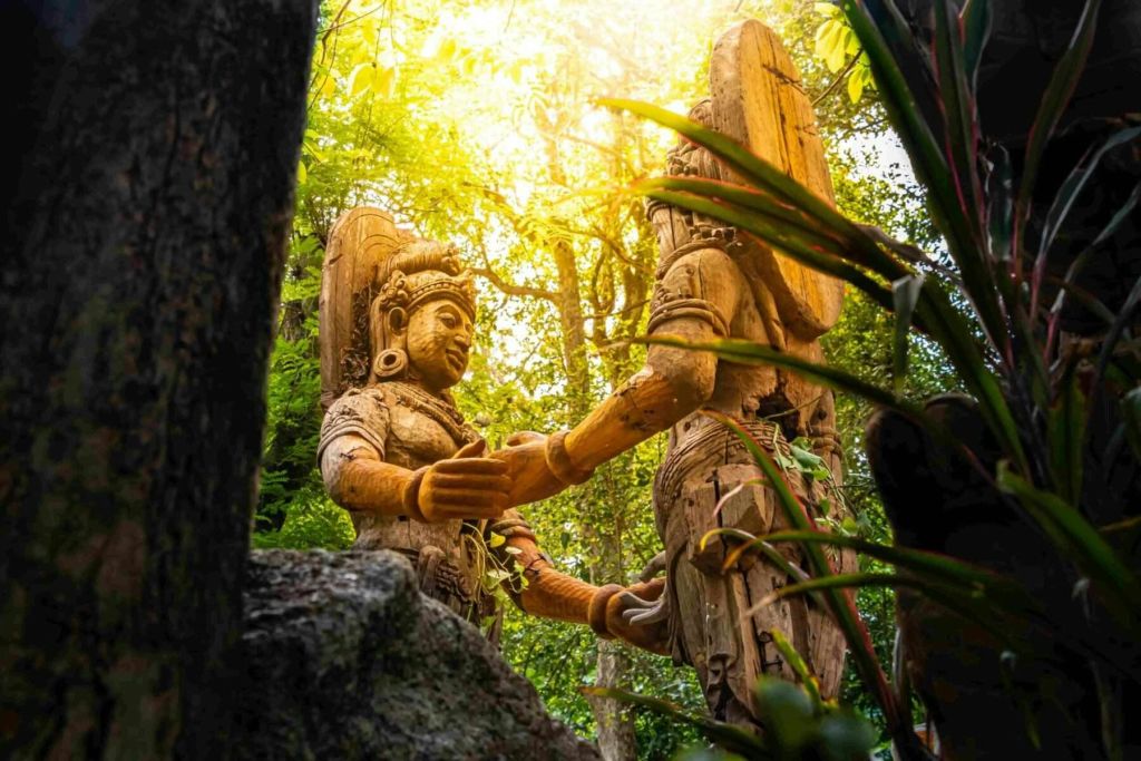 울창한 녹음으로 둘러싸인 두 개의 정교한 목조 조각상이 따뜻한 햇살을 받으며 목욕을 즐기고 있습니다.
