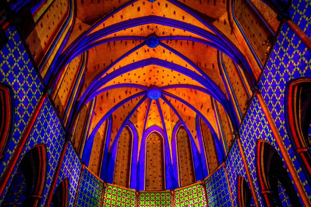 선명한 블루, 오렌지, 그린 패턴과 정교한 디자인이 돋보이는 화려한 고딕 스타일의 아치형 천장.