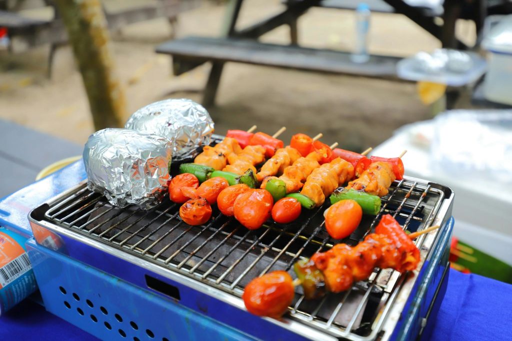 야채와 고기 꼬치, 호일로 감싼 음식, 야외 바비큐 그릴, 피크닉 벤치.