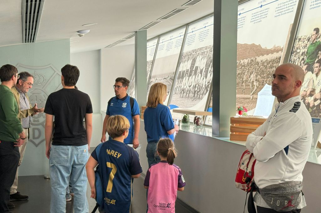 어린이를 포함한 일행이 스포츠 기념품과 역사 사진이 전시된 공간에 서 있습니다.