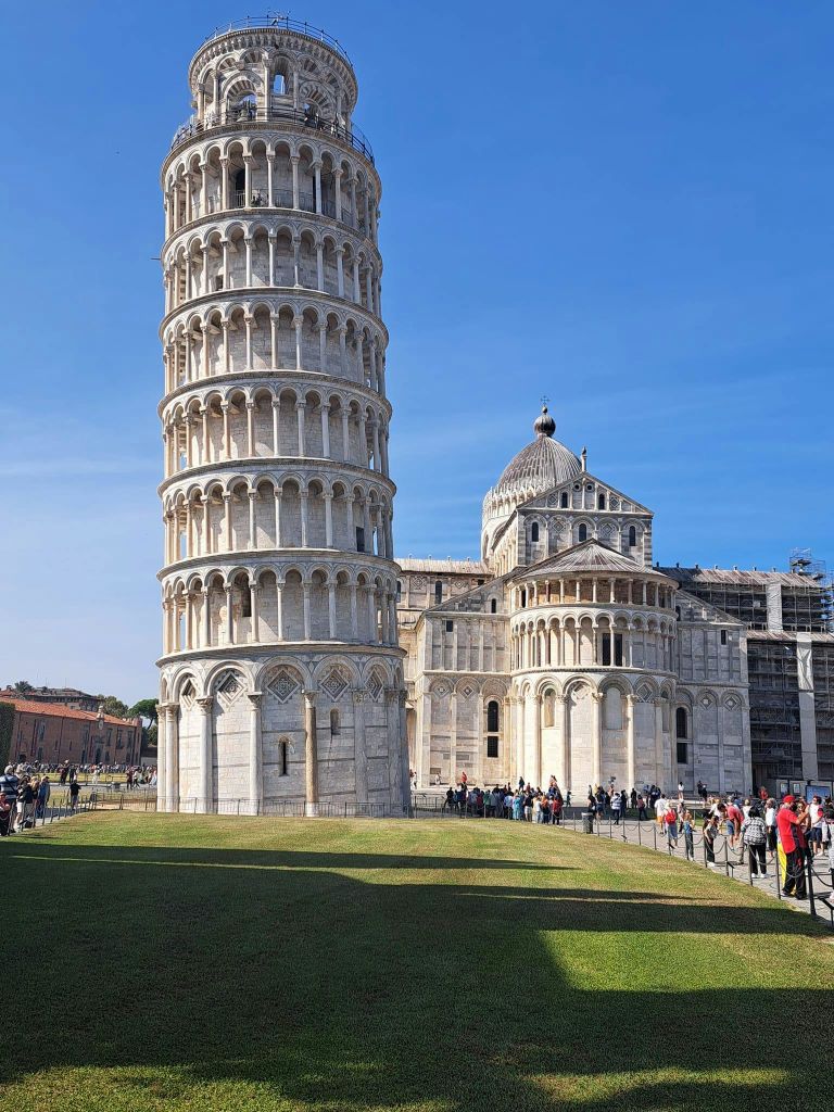 화창한 날 관광객들이 근처에 서서 걷고 있는 피사의 사탑과 주변 대성당.