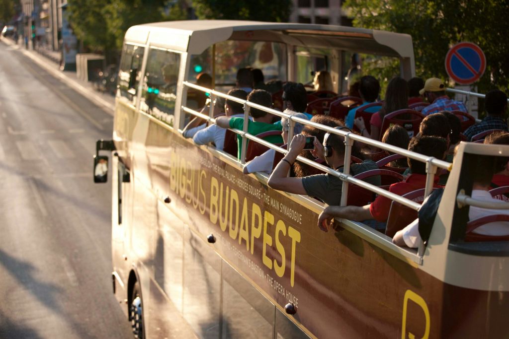 부다페스트의 2층 관광 버스로 상부 탁 트인 갑판에 사람들이 앉아 화창한 날 전망을 감상할 수 있습니다.