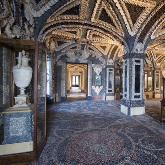 화려한 천장과 벽, 모자이크 바닥, 흰색 꽃병을 수납할 수 있는 유리 디스플레이 케이스, 창문을 통해 빛이 흐르는 복잡한 객실.