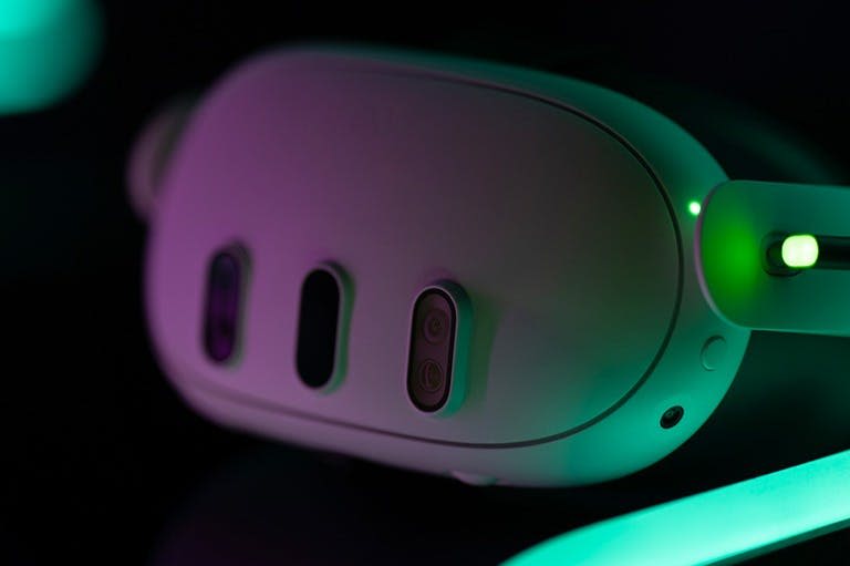 전면에 3개의 센서를 보여주는 녹색 및 보라색 조명 아래 가상 현실 헤드셋의 클로즈업.