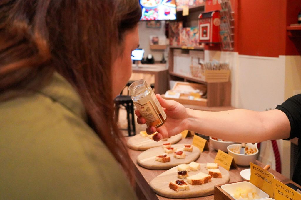 가게에 있는 사람이 다른 사람이 들고 있는 병에서 냄새를 맡고, 빵 한 접시에 샘플을 담아 카운터에 뿌립니다.