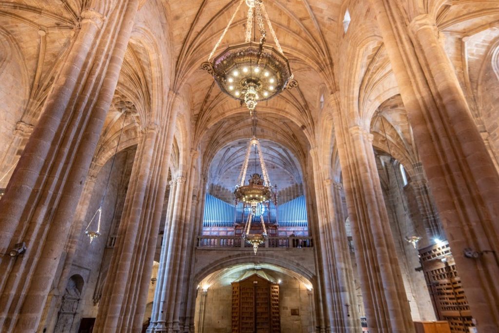 아치형 천장, 화려한 샹들리에, 뒤쪽에 커다란 파이프 오르간이 있는 대성당의 내부.