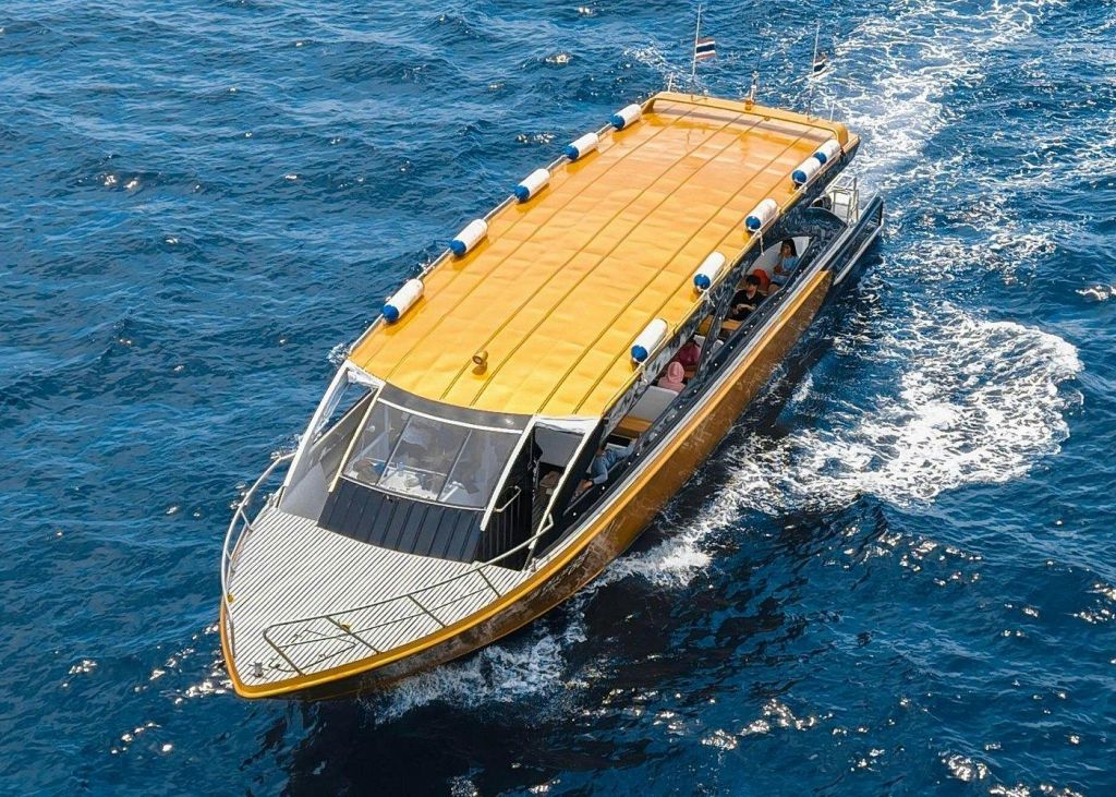 푸른 물 위에 노란 지붕의 배가 돛을 달고 있습니다. 보트 안에는 여러 사람이 보입니다. 깃발은 뒷면에 부착되어 있습니다.