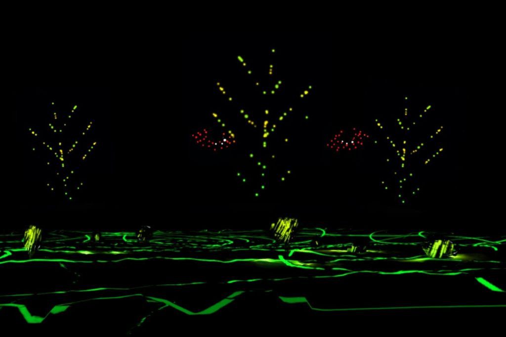 노란색과 빨간색 조명으로 빛나는 녹색 길과 나무가 어둡게 나타나 바닥에 빛나는 패턴을 연출합니다.