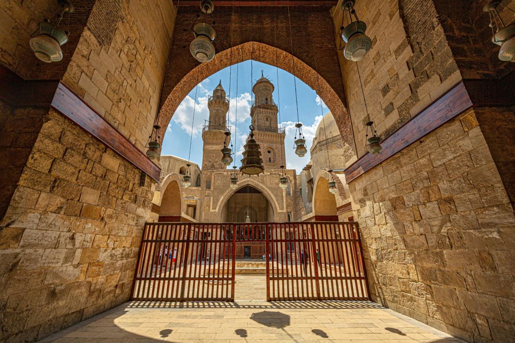 높이 솟은 두 개의 첨탑과 등불이 걸려 있는 안뜰로 이어지는 건축물 아치길의 전망.