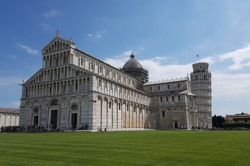 청명한 푸른 하늘을 배경으로 화려한 건축물과 기울어진 탑에 인접한 돔이 있는 커다란 대성당.