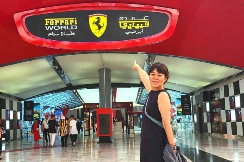 빨간색과 흰색으로 장식된 현대적인 실내 공간에서 페라리 월드 표지판을 가리키는 여성.