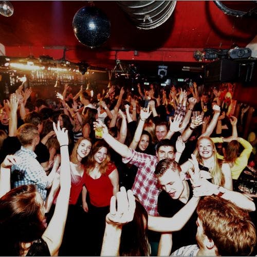 머리 위로 화려한 조명과 디스코 공을 들고 붐비는 나이트클럽에서 춤을 추고 즐기는 사람들이 많습니다.