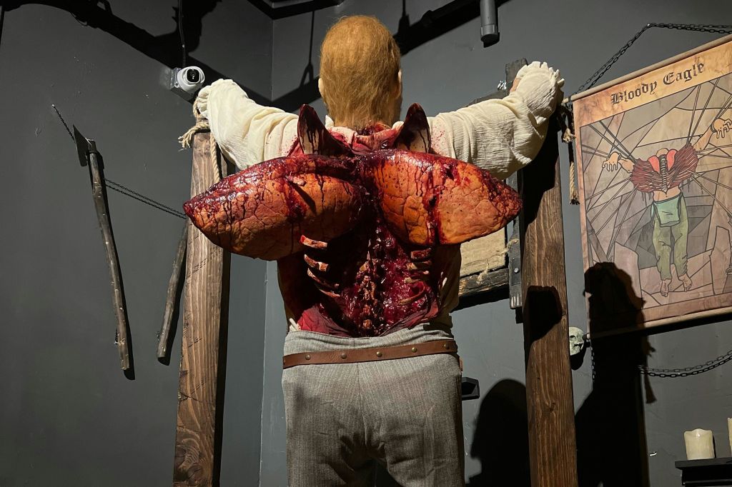 나무 프레임이 있는 희미한 조명 방에서 등에서 커다랗고 그로테스크한 날개 모양의 성장이 나타나는 그림.