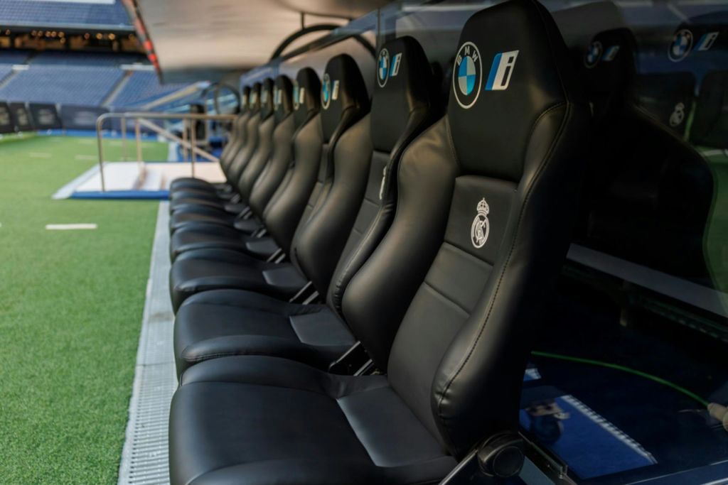 경기장에 검은 가죽 스포츠 좌석이 줄지어 있고 머리 받침대에 BMW와 레알 마드리드의 로고가 보입니다.