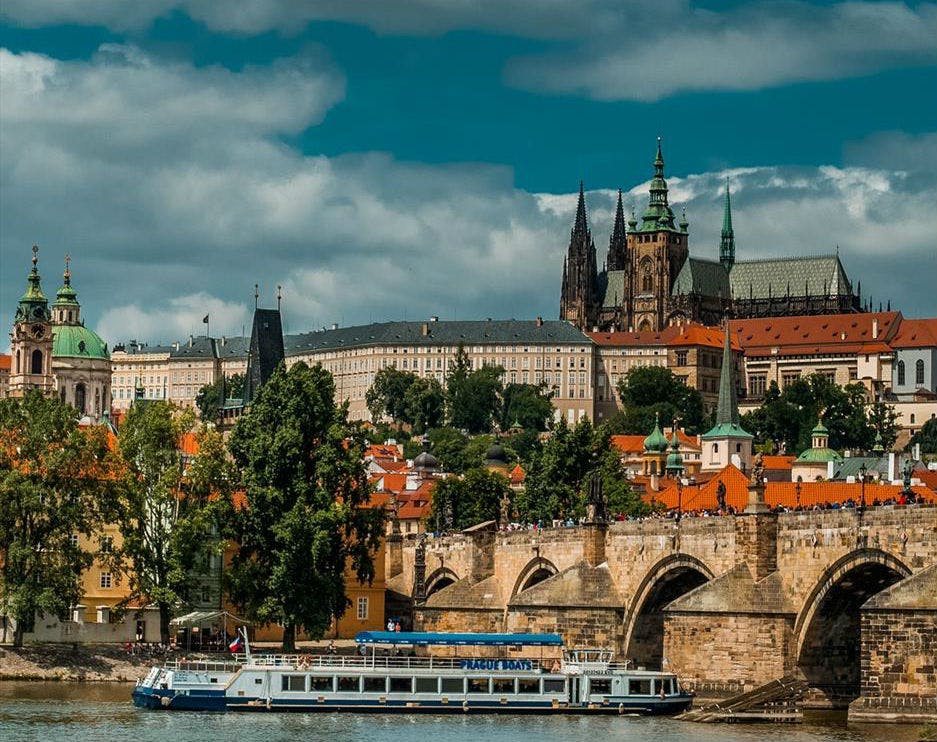 강, 돌다리, 투어 보트, 붉은 지붕이 있는 건물, 첨탑이 있는 대성당이 있는 유서 깊은 유럽 도시 풍경.