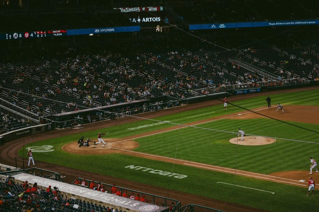 필드에 있는 선수, 스탠드에 있는 팬, 눈에 띄는 광고가 있는 경기장에서 진행 중인 야구 경기.