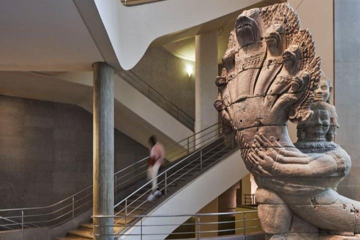 박물관을 배경으로 사람 형상이 그려진 머리가 여러 개인 뱀의 커다란 석조 조각으로, 계단을 배경으로 하고 있습니다.