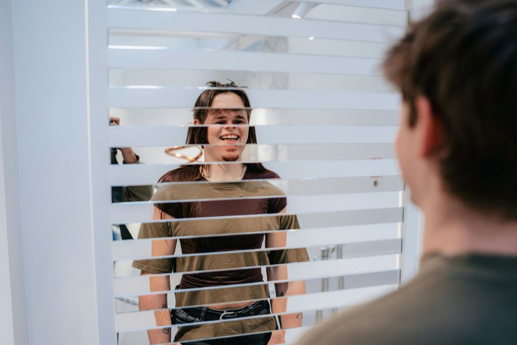 밝은 조명과 모던한 인테리어로 가로 블라인드를 통해 미소를 짓는 사람.