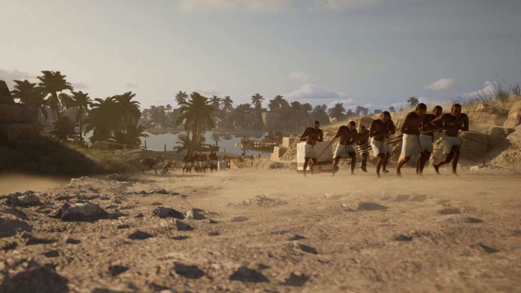 야자수와 강을 배경으로 흰 옷을 입은 한 무리의 남성이 사막 풍경을 가로질러 밧줄을 당깁니다.