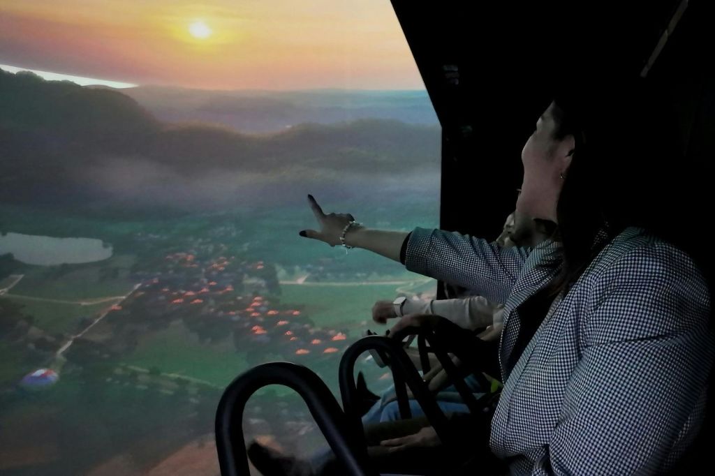 파노라마 화면과 함께 차량에 앉아 석양의 아름다운 풍경을 감상하는 사람들. 한 여성이 화면을 가리킵니다.