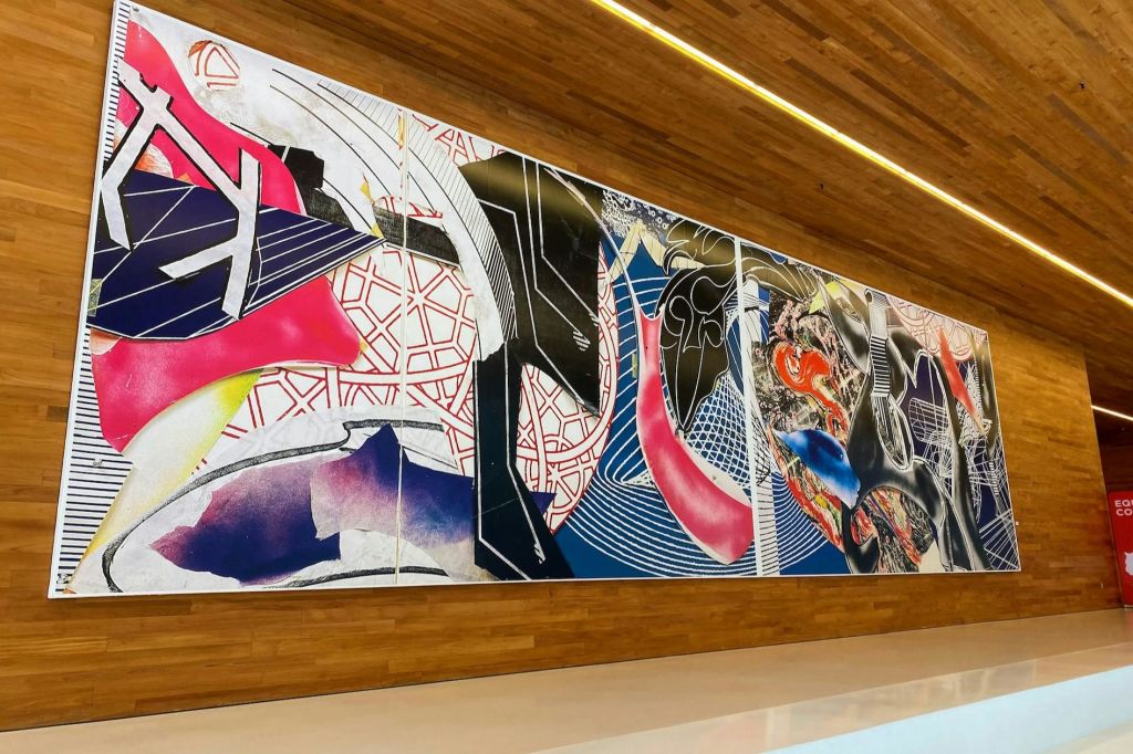 현대적이고 조명이 밝은 공간 내부의 나무 벽에 기하학적 패턴과 모양이 있는 크고 다채로운 추상 벽화.