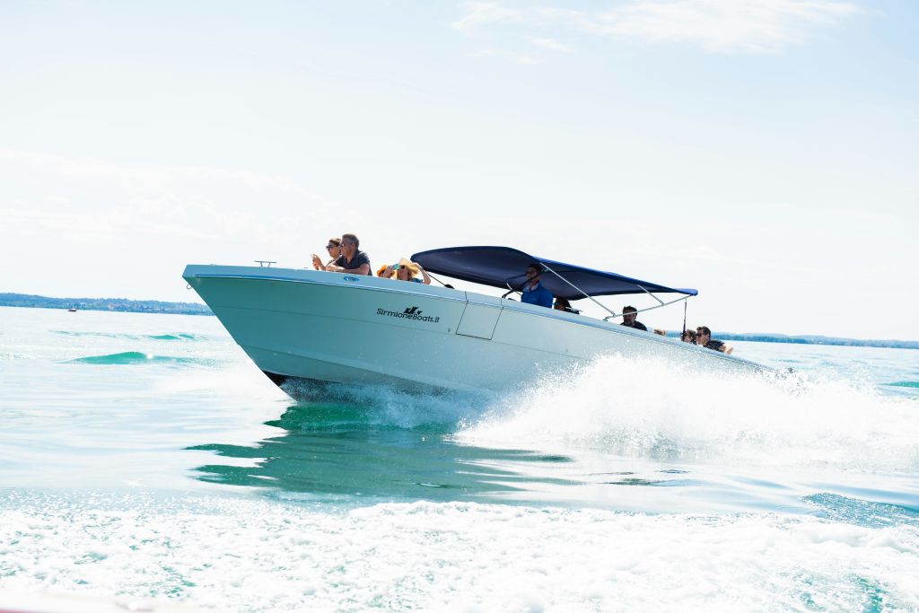 파란색 캐노피가 물 위를 빠르게 이동하는 스피드보트로, 여러 사람이 탑승하여 라이딩을 즐깁니다.