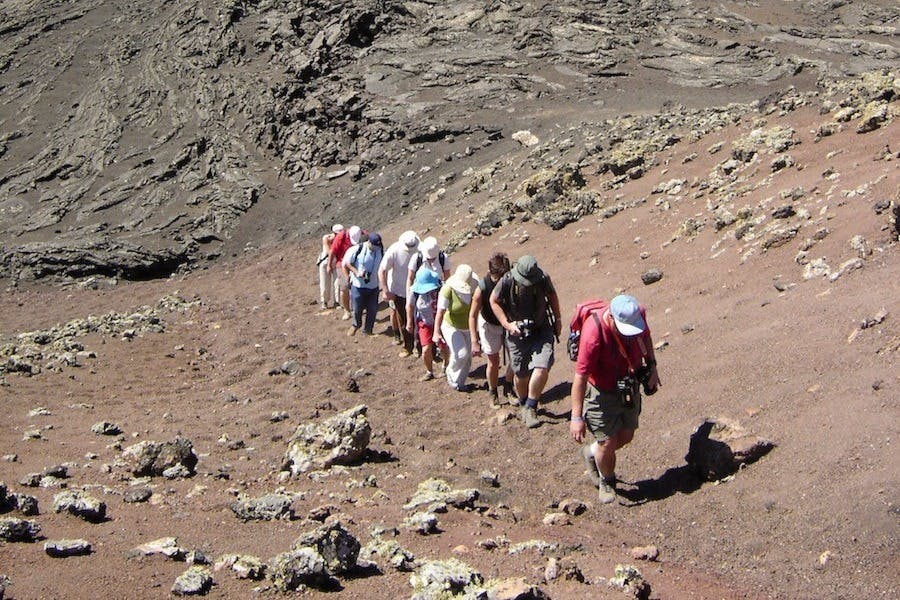 바위투성이의 황량한 지형에서 오르막길을 걷는 등산객들. 하늘이 보이지 않는다.