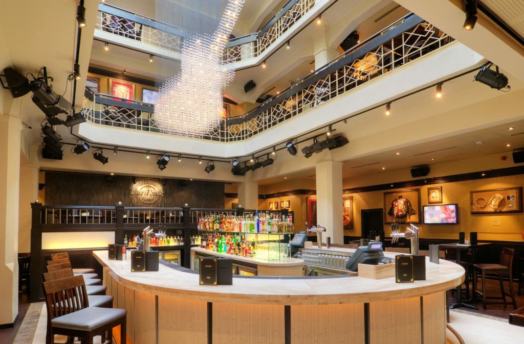 중앙 조명 병 디스플레이, 좌석, 기타 모양의 대형 샹들리에가 있는 다층 공연장의 넓은 바 공간.