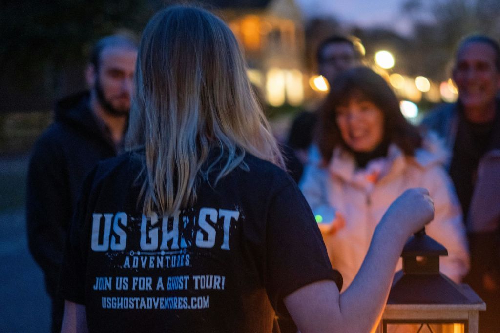 게스트가 귀신 이야기를 듣기 위해 주변을 둘러싸고 있을 때 등불을 들고 있는 투어 가이드