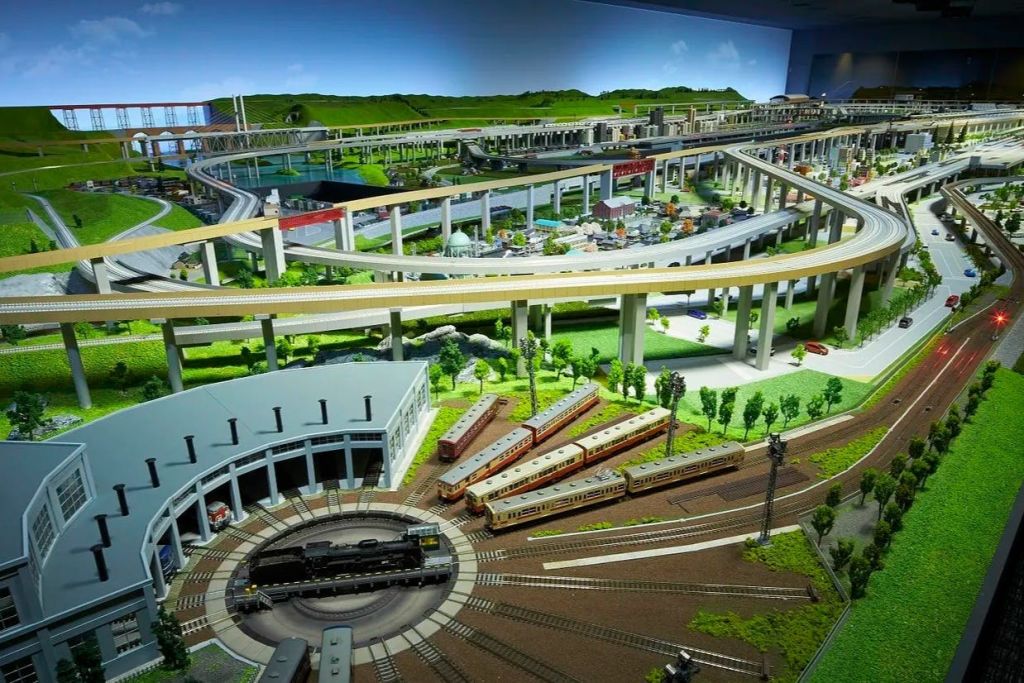 둥근 집, 여러 트랙, 기차 및 조경 구역의 높은 트랙을 특징으로 하는 상세한 모델 기차 레이아웃.