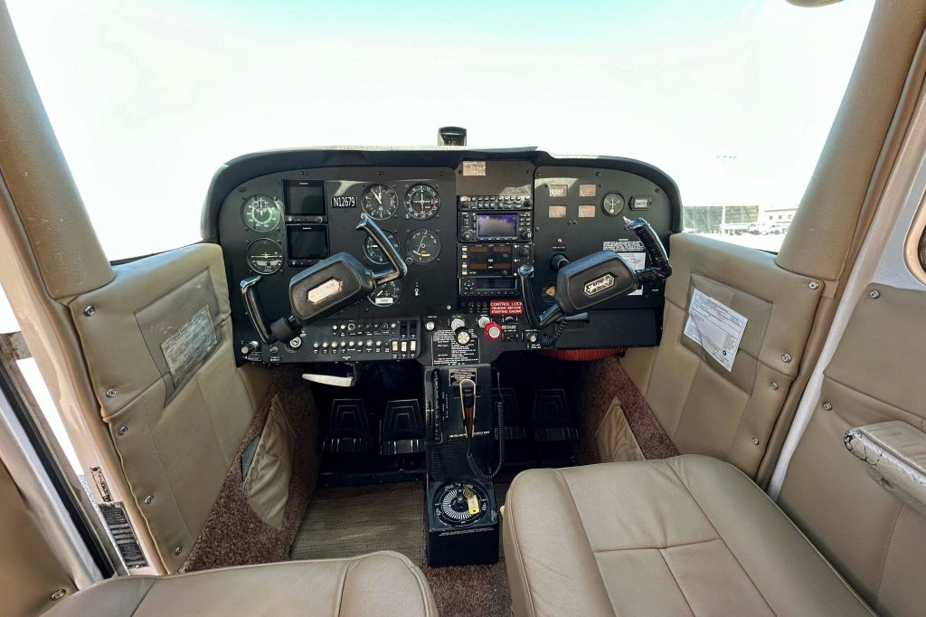 듀얼 컨트롤 요크, 다양한 계측기 게이지, 스위치 및 베이지색 시트가 있는 소형 항공기의 조종석.