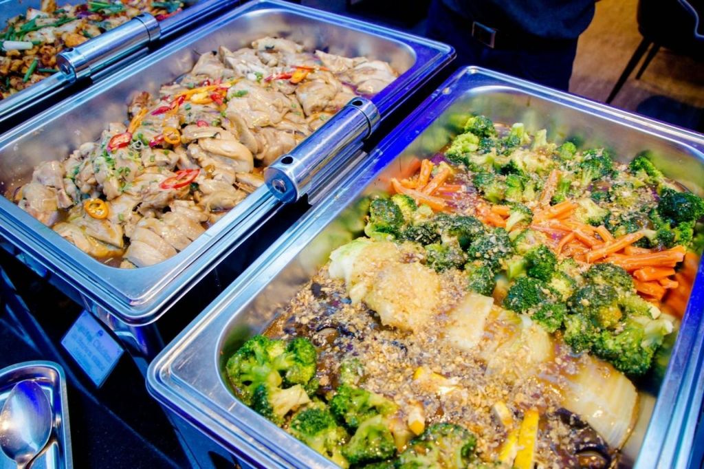 브로콜리를 곁들인 조리된 야채와 칠리로 장식된 고기를 포함한 뷔페 스타일의 음식 쟁반.