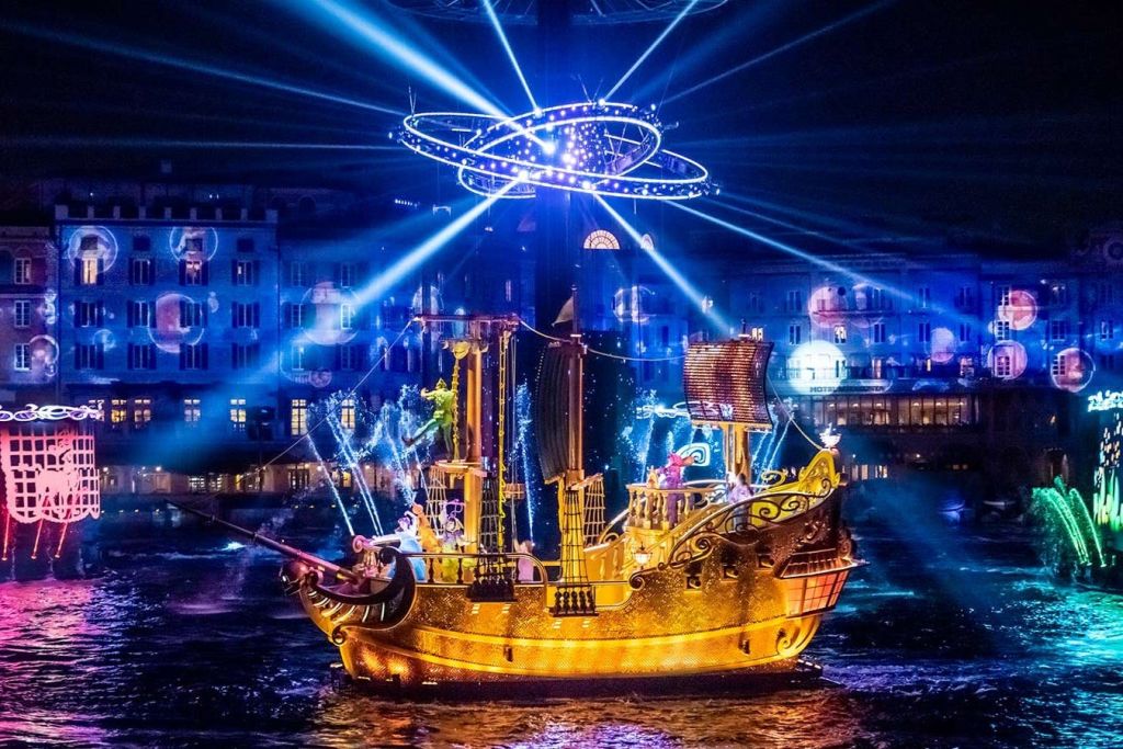 밤에 건물을 배경으로 활기찬 조명과 미래 지향적 인 반지가있는 물 위의 조명 해적선.