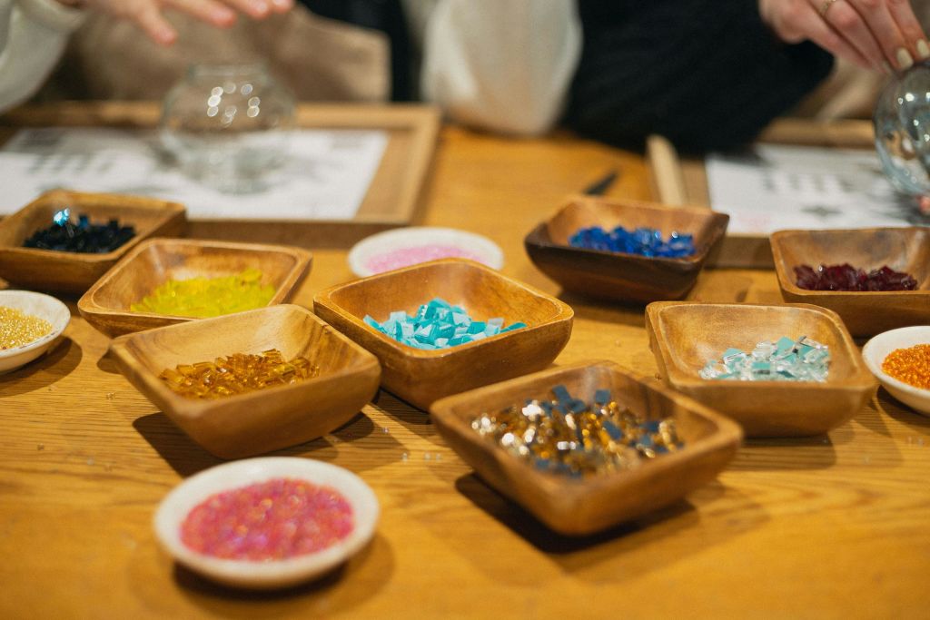 공방 테이블에 다채로운 모자이크 스톤이 가득한 나무 트레이.