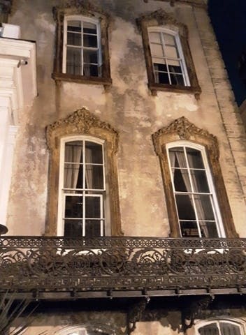 장식용 창문과 화려한 철제 발코니 난간이 있는 오래된 건물의 외관.