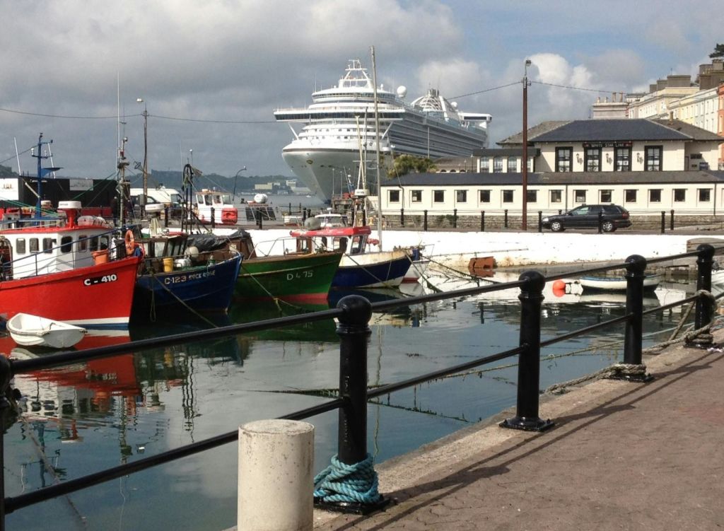 대형 유람선과 건물을 배경으로 항구에 정박한 어선.