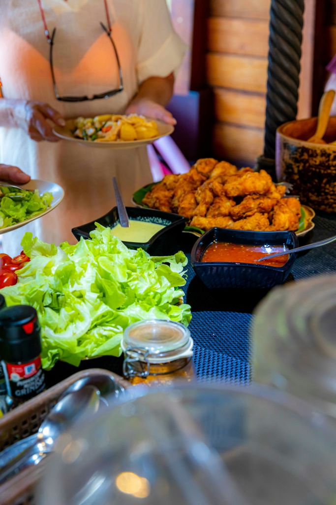 신선한 양상추, 토마토, 튀긴 음식, 디핑 소스 2개, 향신료 용기, 식기가 담긴 테이블입니다.