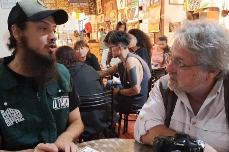 다양한 테이블에서 대화하고 상호 작용하는 활기찬 카페 장면. 두 남자가 대화에 집중하고 있습니다.