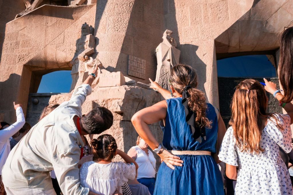 커다란 건축물에서 석조 조각을 가리키고 관찰하는 사람들.