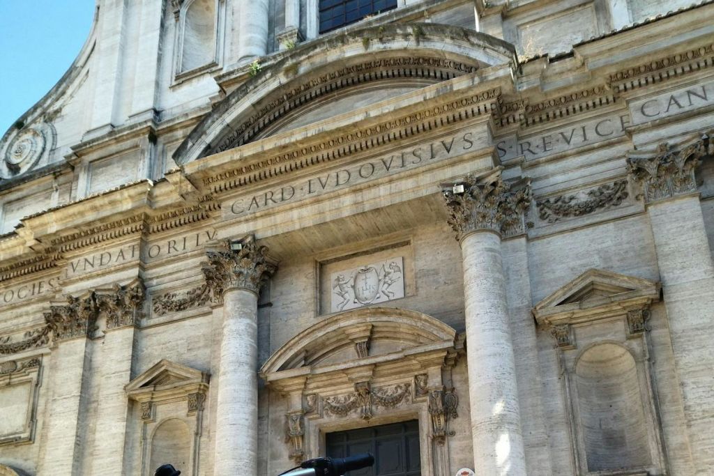 커다란 기둥, 세부 조각, 출입구 위에 라틴 문양이 새겨진 고대 석조 건물의 화려한 외관.