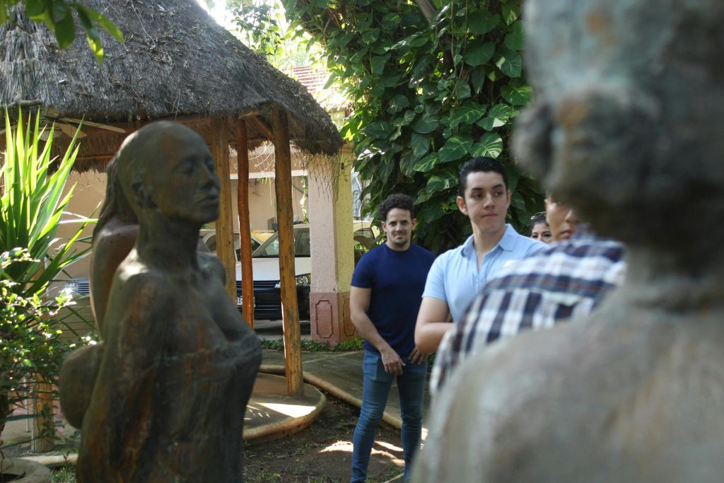 정자 근처 야외에 서 있는 사람들로, 단풍을 배경으로 돌로 만든 조형물이 눈앞에 펼쳐집니다.