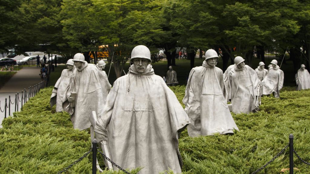 관목과 나무 사이에는 비옷과 헬멧을 쓴 군인들의 동상이 세워져 있으며, 추모 분위기의 군사 장면이 묘사되어 있습니다.
