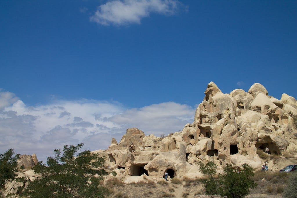 푸른 하늘 아래 천연 동굴이 있는 암석 지층과 앞쪽에는 구름과 희박한 녹지가 있습니다.