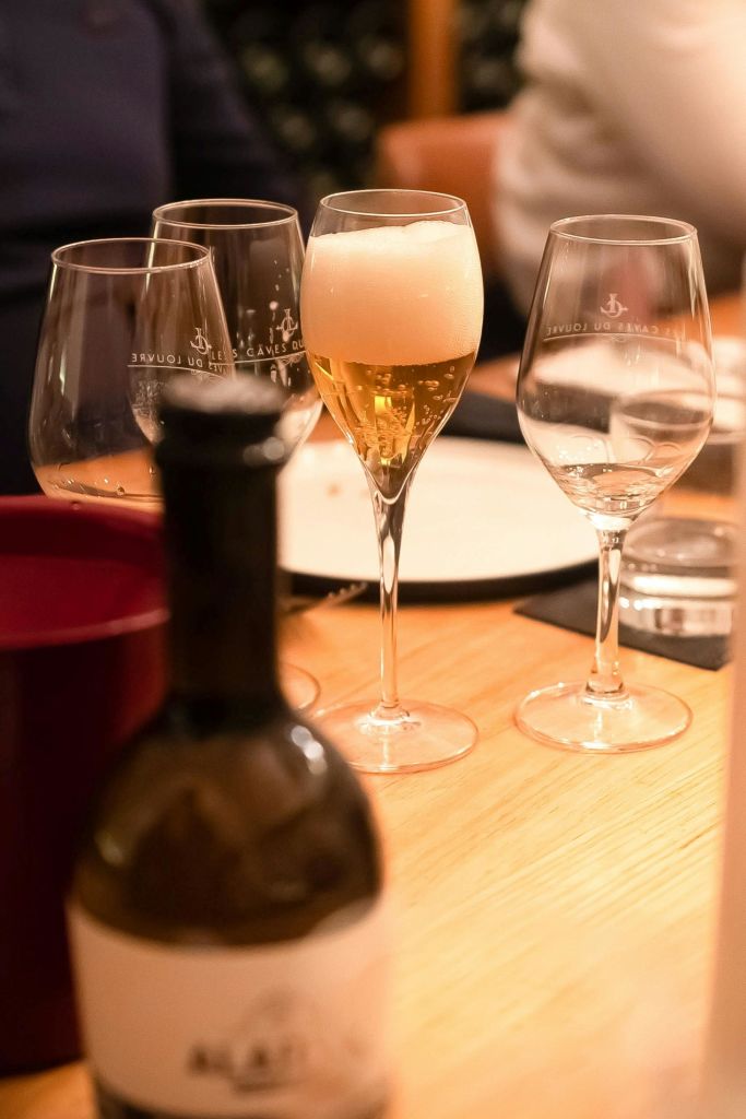 샴페인을 포함한 유리잔이 놓인 식탁과 앞쪽에 흐릿한 병이 있습니다.