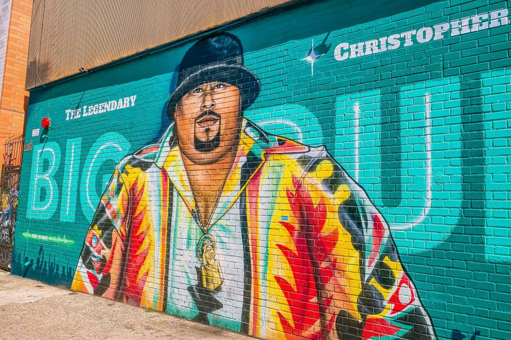 활기찬 셔츠와 검은 모자를 쓰고 벽돌 벽에 "전설" 과 "크리스토퍼" 라고 쓰여진 화려한 벽화.