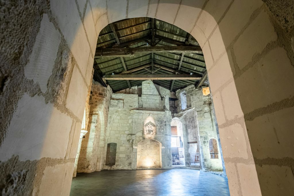 나무 대들보 천장, 아치형 출입구, 대형 아치를 통해 볼 수 있는 매끄러운 바닥이 있는 유서 깊은 석조 건물의 내부.